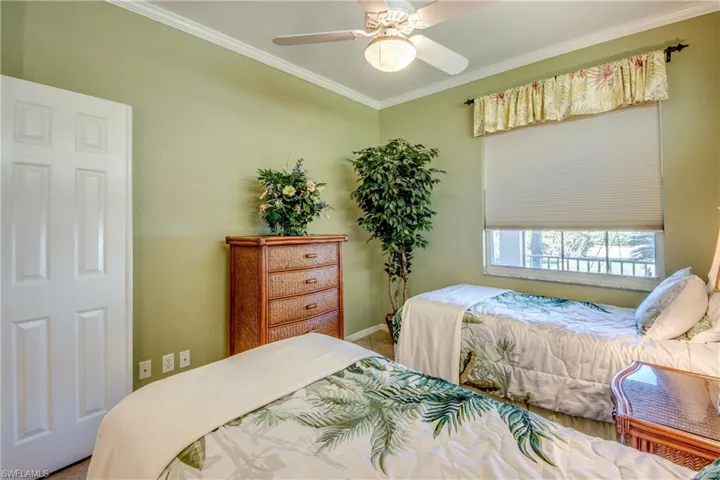 Bedroom featuring a white ceiling fan, textured walls, a single-panel interior door, and a horizontal window with a cellular shade