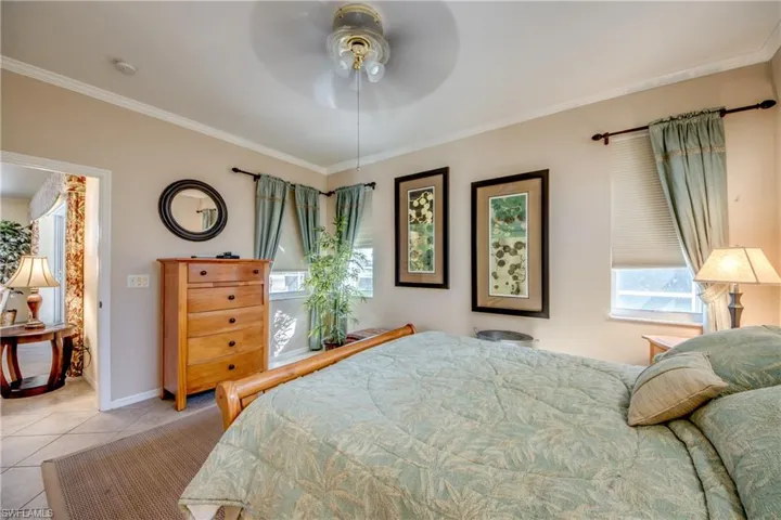 Neutral-toned room featuring crown molding, neutral wall finishes, tile flooring, and a ceiling fan with light fixture