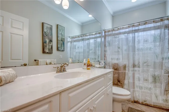 Bathroom featuring a white vanity cabinet with an integrated sink, stone-finish countertop, polished metal faucet, and full-width vanity mirror