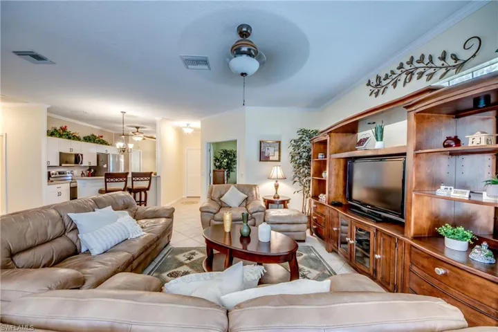 Open-concept living space featuring ceramic tile flooring, built-in wooden cabinetry, recessed ceiling lighting, and a dual-purpose ceiling fan fixture