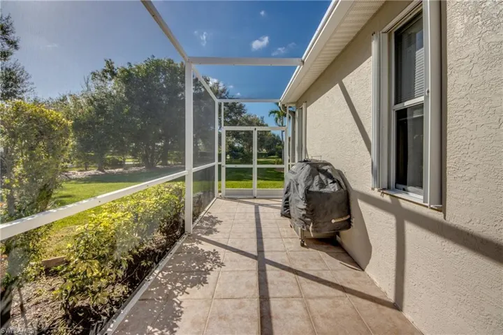 Screen-enclosed patio featuring ceramic tile flooring, stucco exterior wall, and window with white frame