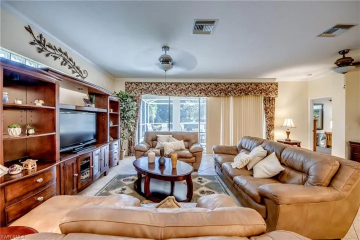 Custom built-in wooden shelving unit with integrated cabinetry, ceiling fans, tile flooring, and sliding glass doors