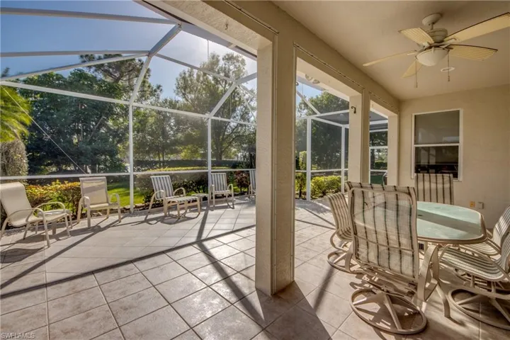 Covered patio featuring ceramic tile flooring, a screen enclosure, and a ceiling fan