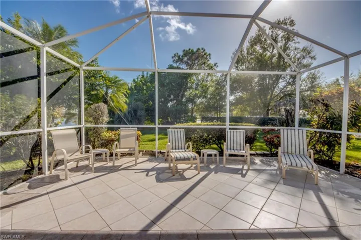 Screened-in patio featuring white aluminum framing, diamond-pattern tile flooring, and mature landscaping