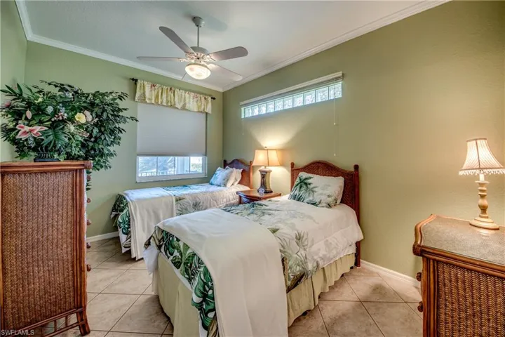 Room featuring diagonal-laid tile flooring, crown molding, a central ceiling fan with integrated lighting, and a high-set horizontal transom window