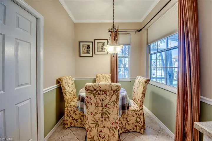 Dining area featuring tile flooring, wainscoting, dual-pane windows, and a bowl-style pendant light fixture