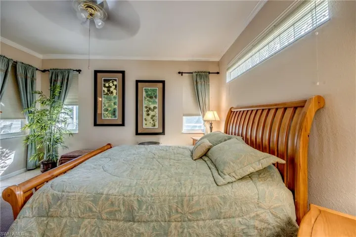 Neutral-toned room featuring a high-positioned clerestory window, multiple multi-pane windows, and a ceiling-mounted fan with integrated lighting