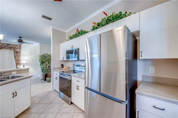 Kitchen featuring white cabinetry, stainless steel appliances, and solid-surface countertops with tile flooring