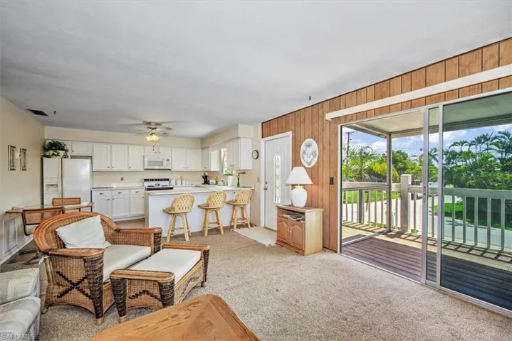 Carpeted living room featuring ceiling fan and wood walls