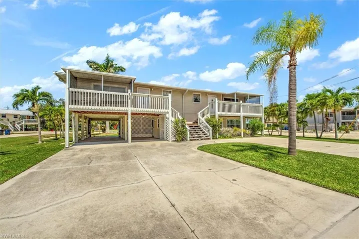 View of front of property with a carport, covered porch, and a front lawn