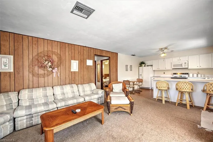 Living room with ceiling fan and wood walls
