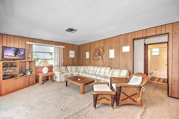 Living room featuring wooden walls and light colored carpet