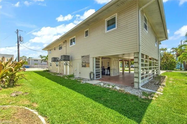 Rear view of house with cooling unit and a lawn