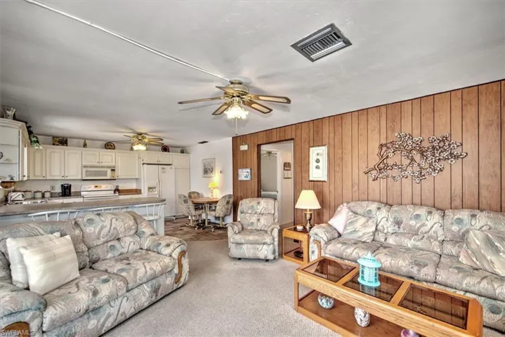 Living room featuring wooden walls, light colored carpet, and ceiling fan