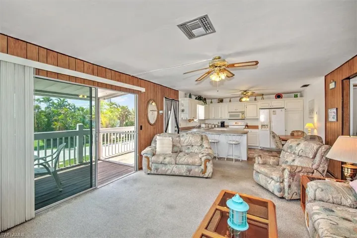 Living room featuring light colored carpet, ceiling fan, and wood walls