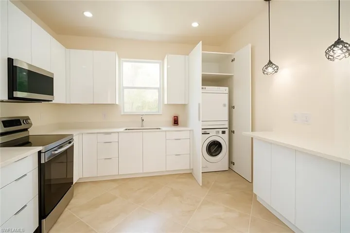 Kitchen featuring stainless steel appliances, white cabinets, modern cabinets, pendant lighting, and light tile patterned flooring