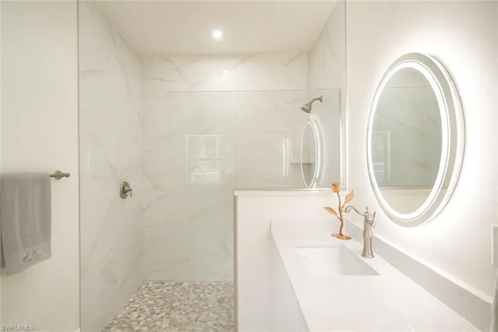 Bathroom with a marble finish shower and vanity