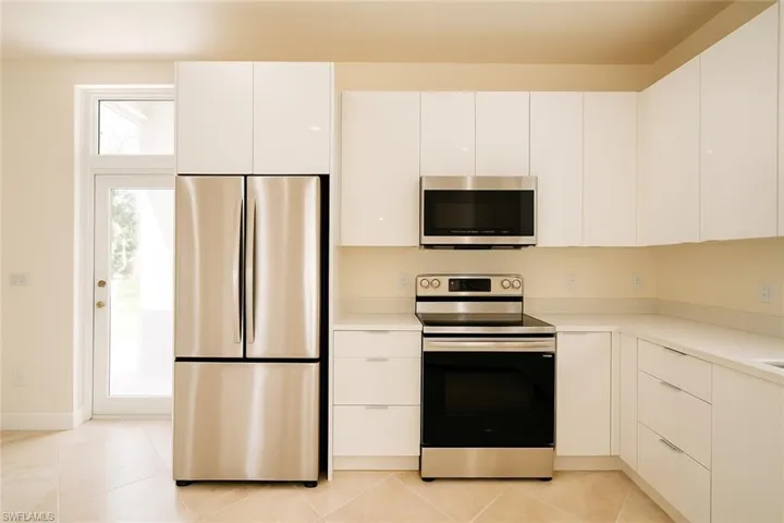 Kitchen with modern cabinets, stainless steel appliances, white cabinets, and light tile patterned floors