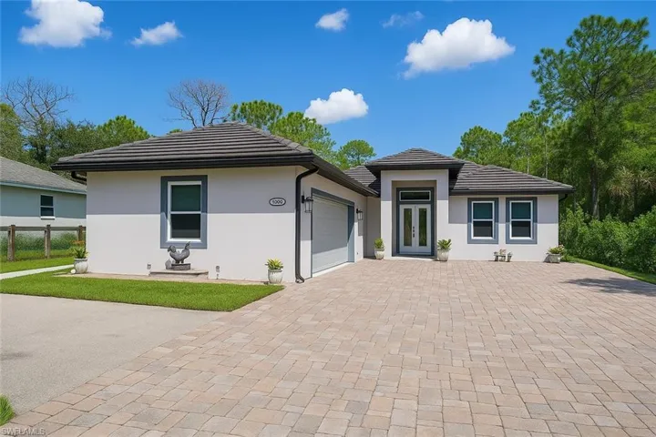 View of front of house featuring decorative driveway, a garage, a tiled roof, and stucco siding