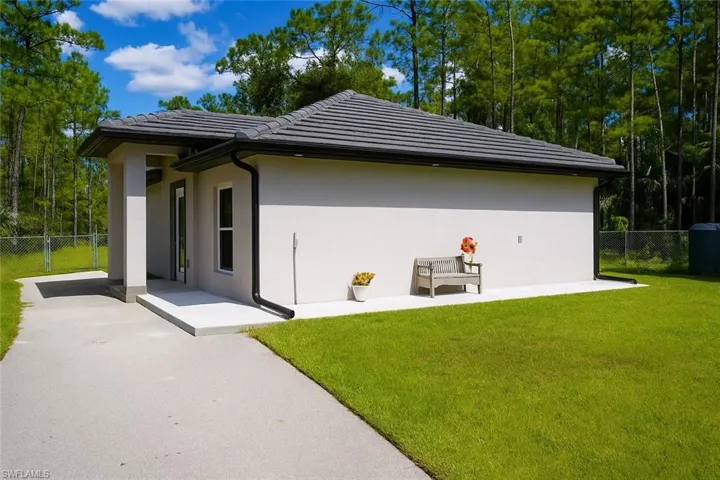 View of property exterior with a tile roof, stucco siding, and a patio