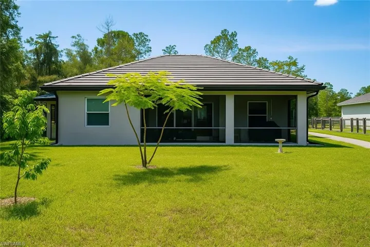 Rear view of property featuring a tile roof, a sunroom, and stucco siding