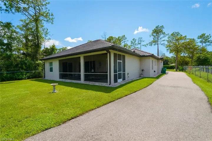 Rear view of property featuring a tile roof, stucco siding, and a sunroom