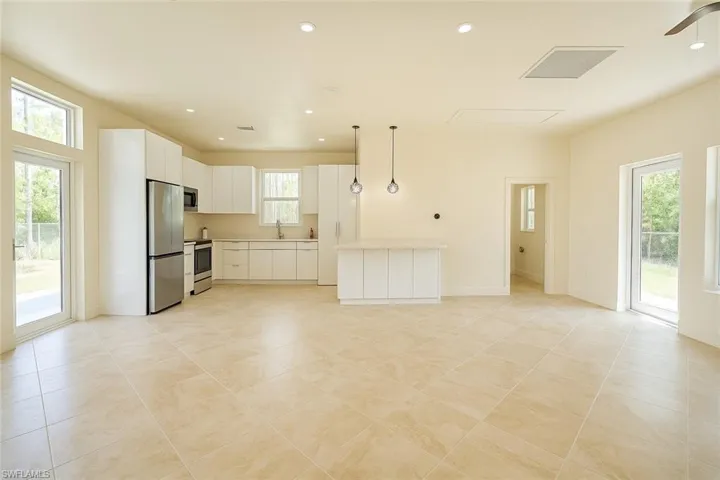 Kitchen featuring healthy amount of natural light, hanging light fixtures, recessed lighting, light countertops, and white cabinetry