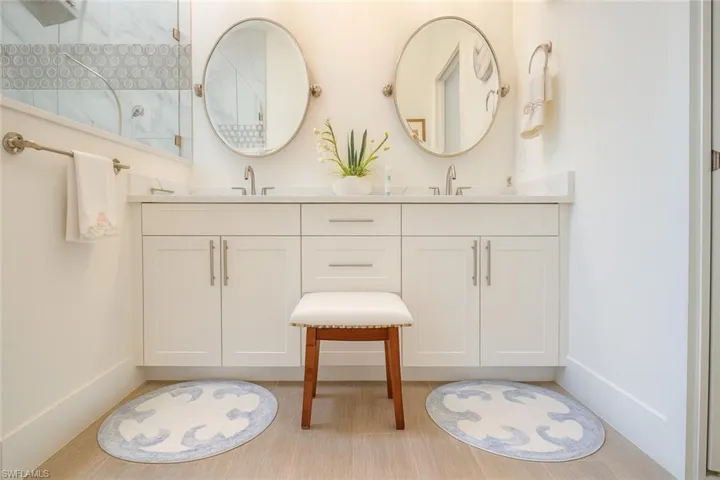 Bathroom featuring double vanity, walk in shower, and light wood-style floors