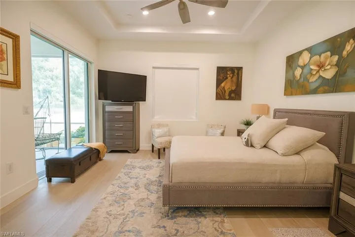 Bedroom featuring a tray ceiling, light wood-style floors, a ceiling fan, and recessed lighting
