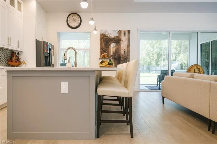 Kitchen featuring glass insert cabinets, white cabinets, decorative light fixtures, and stainless steel refrigerator with ice dispenser