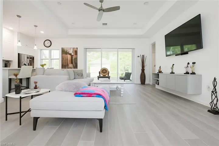 Bedroom featuring a tray ceiling, stainless steel refrigerator, a ceiling fan, light wood finished floors, and recessed lighting
