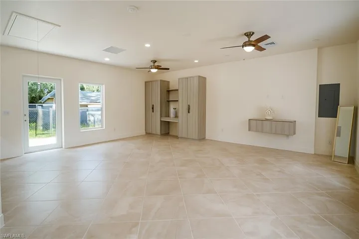 Unfurnished living room featuring attic access, recessed lighting, light tile patterned floors, ceiling fan, and electric panel