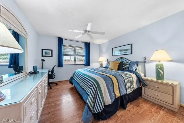 Bedroom with light wood-type flooring, ceiling fan, and a textured ceiling