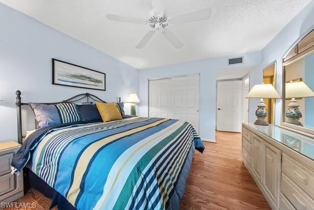 Bedroom featuring a closet, light wood finished floors, a ceiling fan, and a textured ceiling