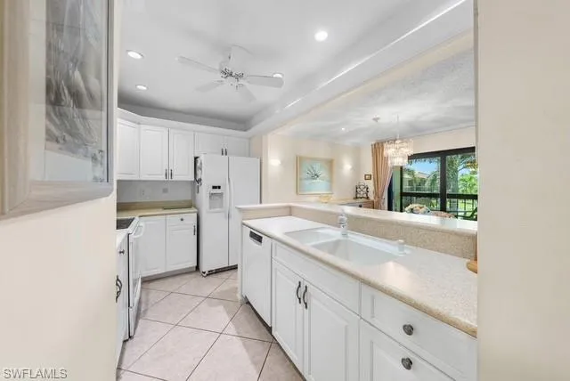 Kitchen featuring light countertops, white cabinets, white appliances, a ceiling fan, and light tile patterned flooring