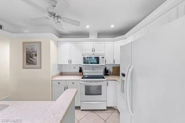 Kitchen featuring white appliances, white cabinets, a ceiling fan, light tile patterned flooring, and recessed lighting