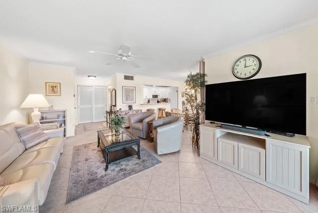 Living area with ornamental molding, a ceiling fan, and light tile patterned floors