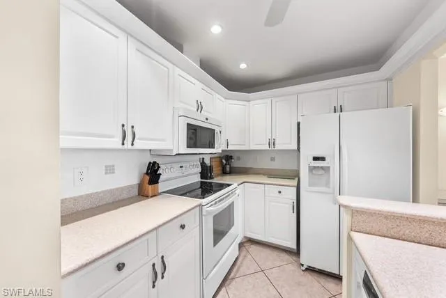 Kitchen featuring white appliances, white cabinetry, light tile patterned floors, a ceiling fan, and recessed lighting