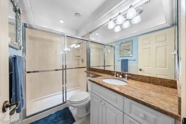 Bathroom featuring vanity, a stall shower, light tile patterned floors, and ornamental molding