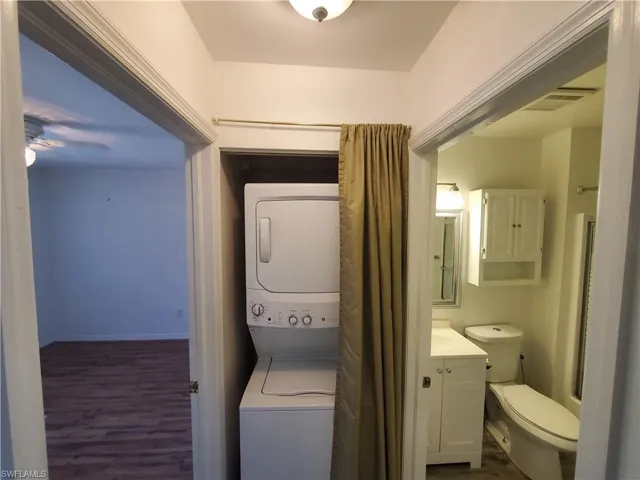 Bathroom with stacked washer and clothes dryer, toilet, and oversized vanity