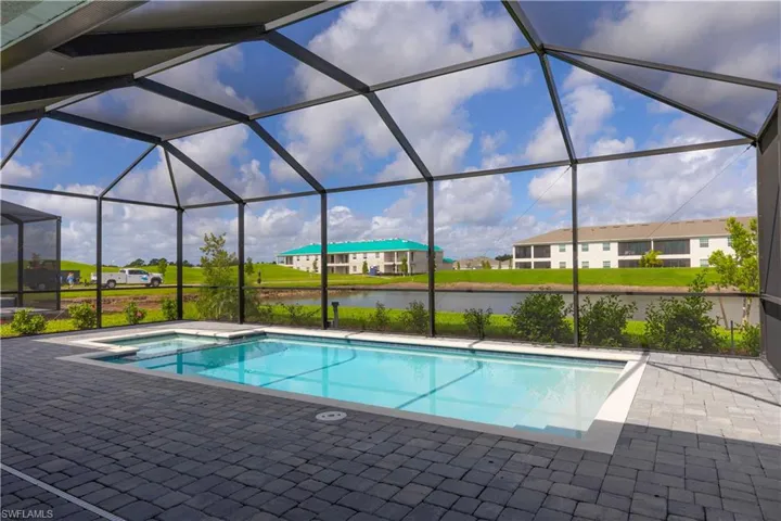 Swimming pool with a sunroom, a water view, a residential view, and glass enclosure