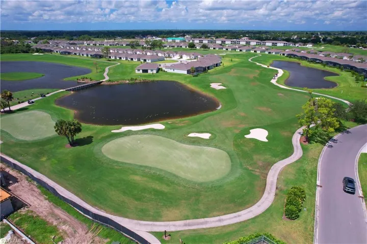 Aerial view of property and surrounding area featuring nearby suburban area, a nearby body of water, and a local golf course