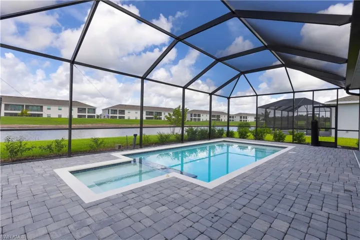 View of swimming pool featuring a sunroom, a pool with connected hot tub, a water view, and glass enclosure