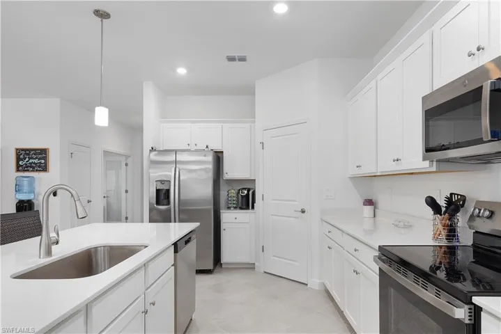 Kitchen with appliances with stainless steel finishes, decorative light fixtures, white cabinetry, light stone countertops, and recessed lighting