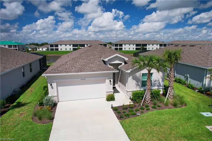 View of front of home with an attached garage, driveway, a front yard, and stucco siding