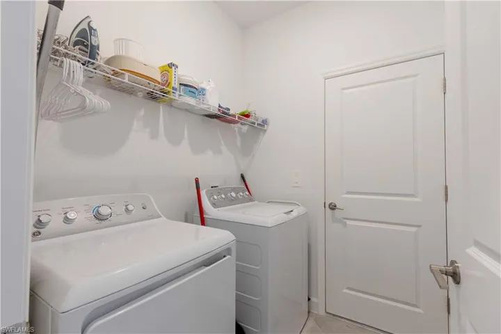 Laundry room with light tile patterned floors and washer and clothes dryer