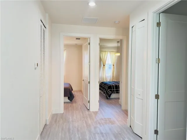 Hallway with light wood finished floors and recessed lighting