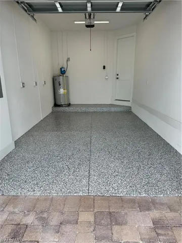 Garage featuring electric water heater and a garage door opener