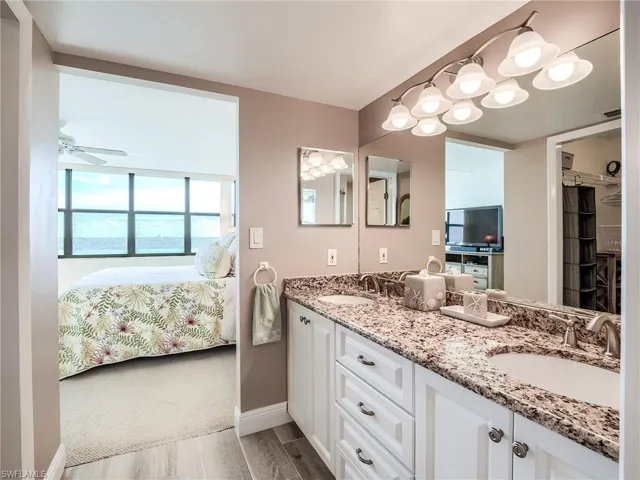 Master bathroom with dual sinks, ceiling fan, vanity with extensive cabinet space, and porcelain tile floors
