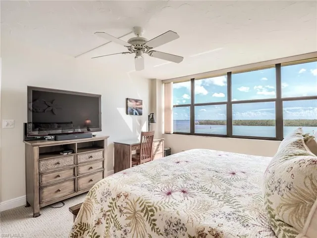 Carpeted master bedroom with ceiling fan and expansive water views of the back bay
